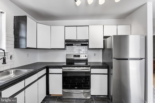 kitchen with appliances with stainless steel finishes, dark countertops, white cabinets, and under cabinet range hood