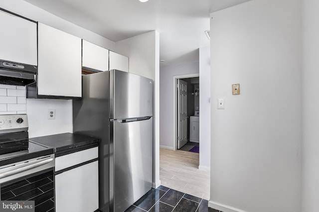 kitchen with white cabinetry, range hood, appliances with stainless steel finishes, wood tiled floor, and dark countertops