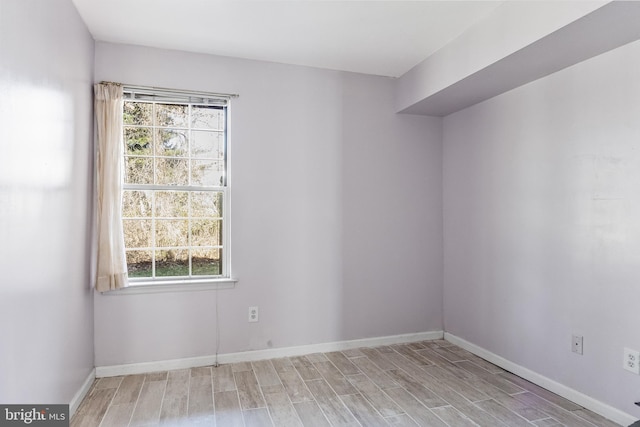 unfurnished room featuring baseboards and light wood finished floors