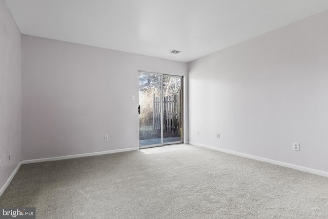 unfurnished room with carpet floors, visible vents, and baseboards