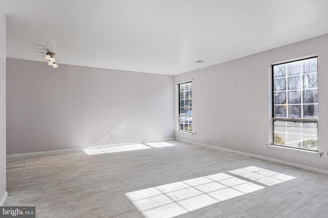 empty room with wood finished floors, visible vents, and baseboards