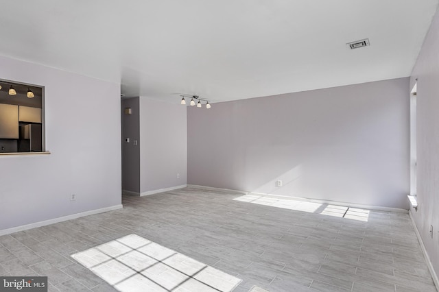 spare room featuring baseboards, visible vents, and track lighting