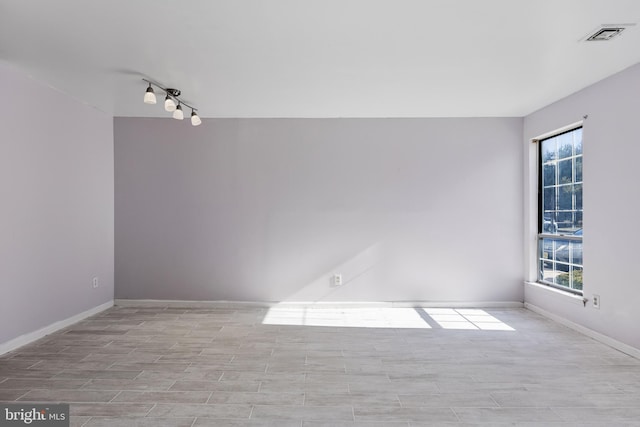 spare room with wood finish floors, visible vents, and baseboards