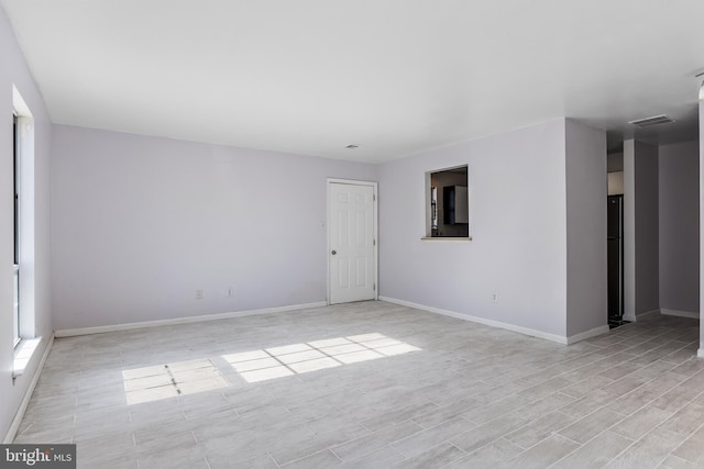 unfurnished room featuring light wood-style floors, visible vents, and baseboards