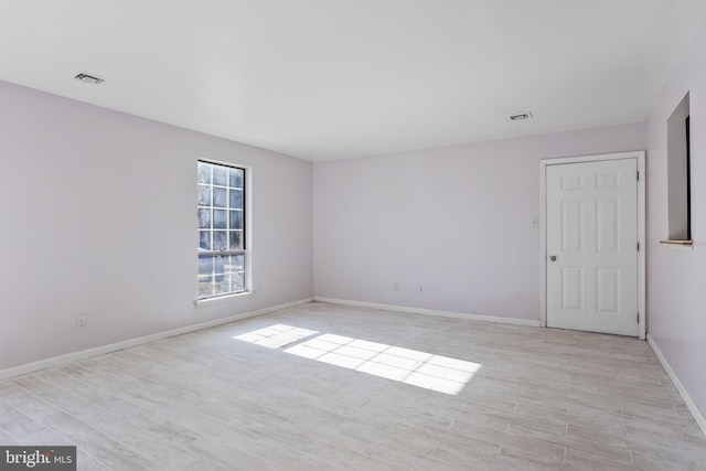 empty room featuring light wood finished floors, baseboards, and visible vents