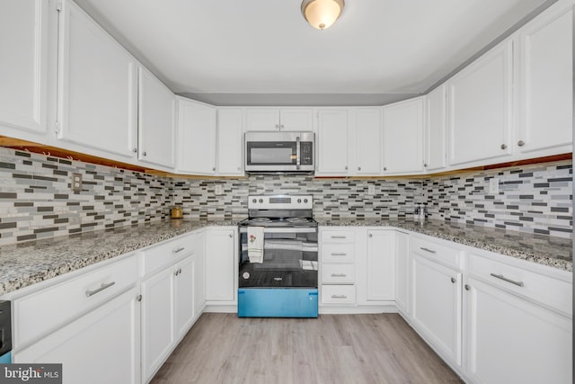 kitchen with light wood-type flooring, appliances with stainless steel finishes, decorative backsplash, and white cabinets