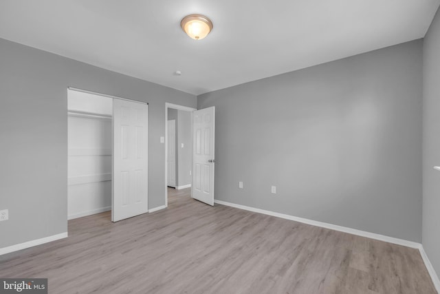 unfurnished bedroom with a closet, baseboards, and wood finished floors