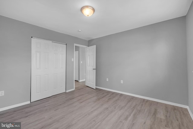 unfurnished bedroom with a closet, baseboards, and wood finished floors