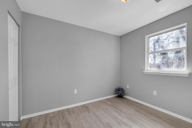 spare room featuring baseboards and wood finished floors