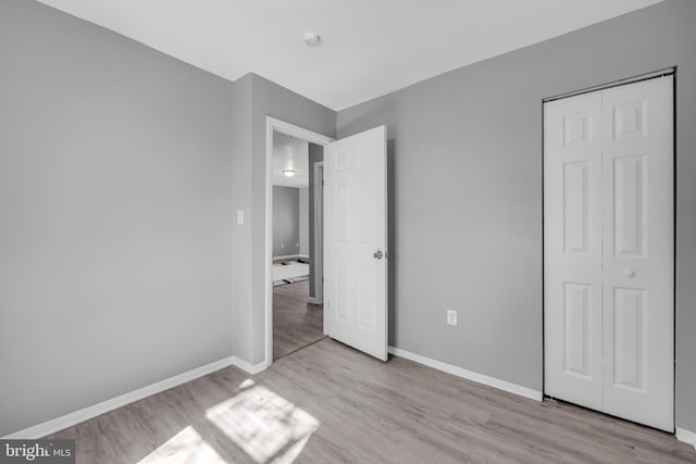 unfurnished bedroom with a closet, wood finished floors, and baseboards