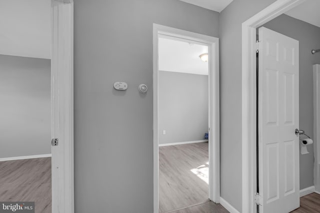 hall with baseboards and wood finished floors