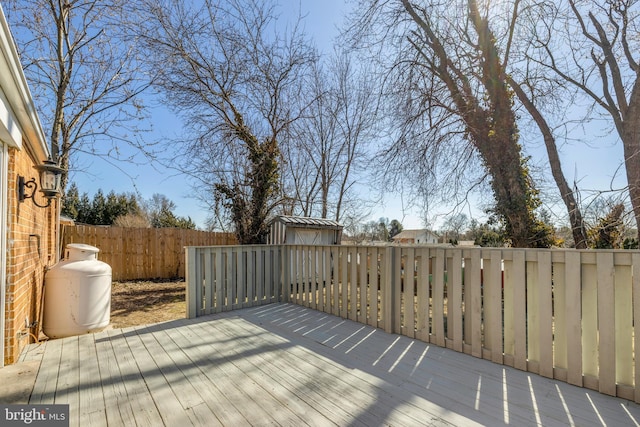 wooden deck with a fenced backyard, a storage unit, and an outdoor structure