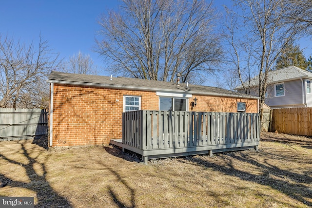 rear view of property with brick siding, a wooden deck, and fence