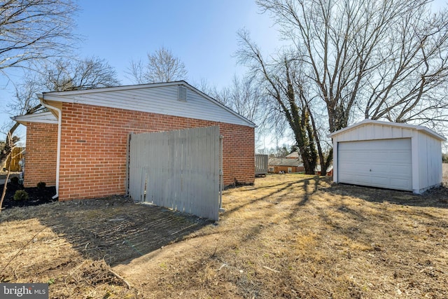 view of home's exterior featuring a garage, brick siding, and an outdoor structure