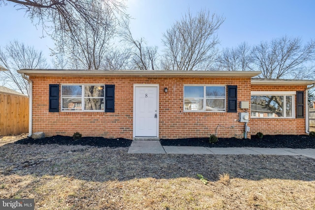 bungalow featuring brick siding and fence