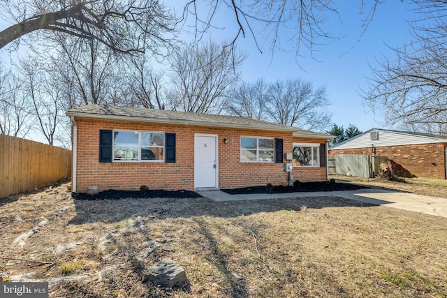 view of front of home with a shingled roof, fence, and brick siding