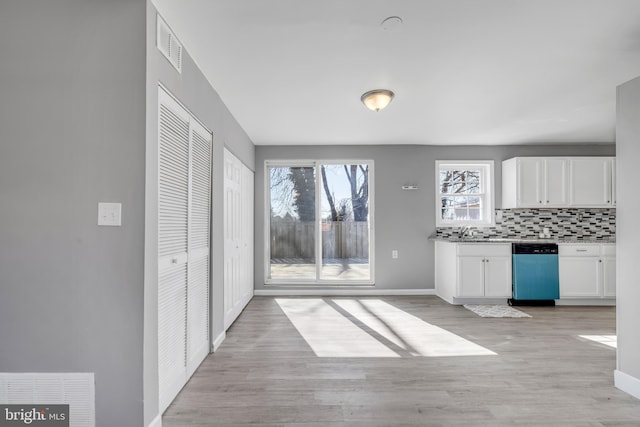 kitchen with a wealth of natural light, decorative backsplash, white cabinets, and dishwasher