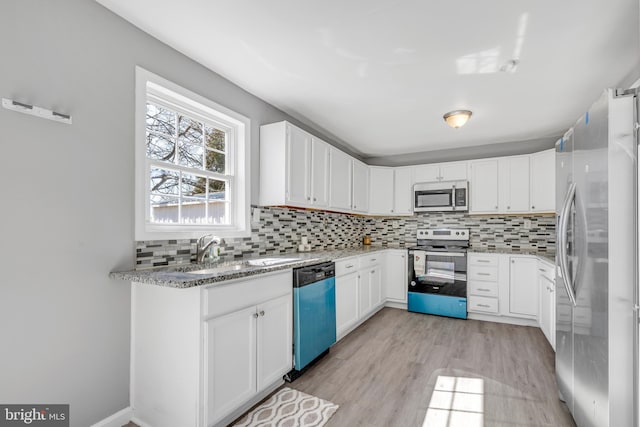 kitchen with stainless steel appliances, white cabinets, light stone counters, and decorative backsplash