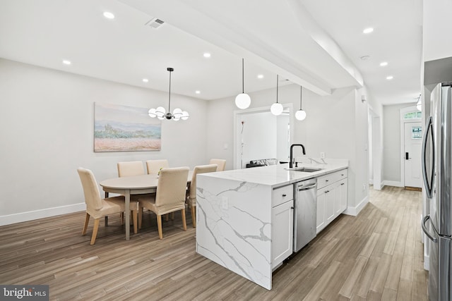 kitchen featuring a peninsula, stainless steel appliances, light wood-style floors, a sink, and recessed lighting