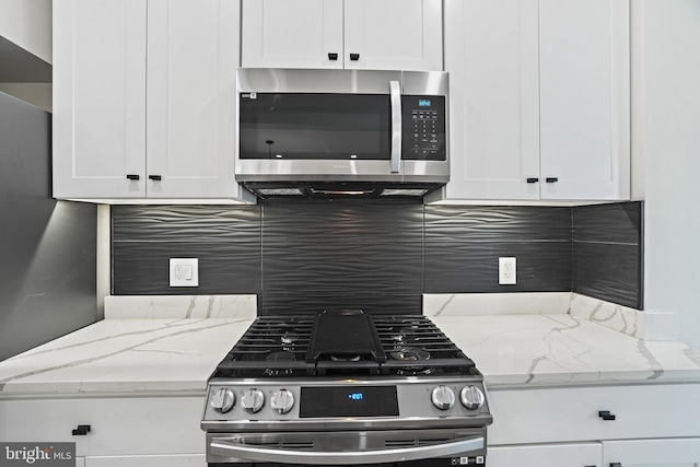 kitchen featuring appliances with stainless steel finishes, backsplash, light stone counters, and white cabinets