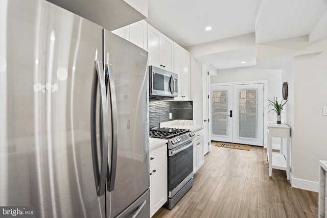 kitchen featuring white cabinets, appliances with stainless steel finishes, light countertops, french doors, and light wood-type flooring