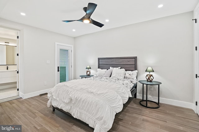 bedroom featuring a barn door, recessed lighting, wood finished floors, a ceiling fan, and baseboards