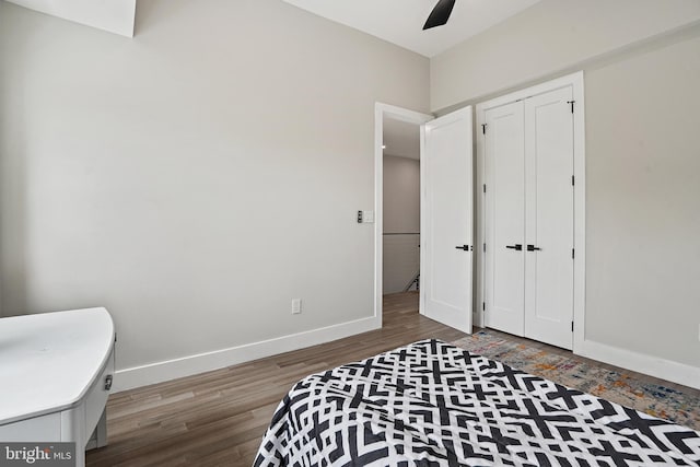 bedroom featuring a ceiling fan, a closet, baseboards, and wood finished floors