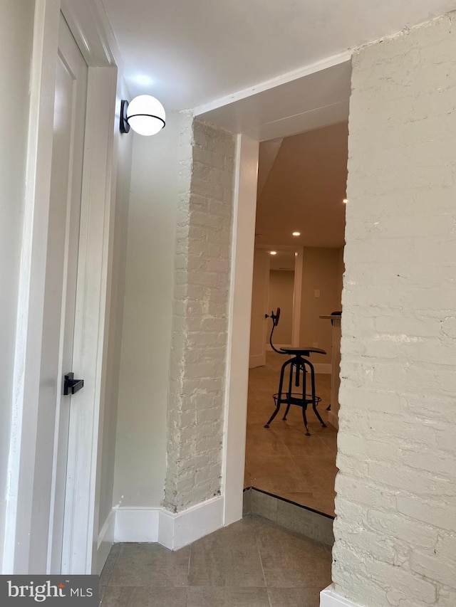 corridor featuring brick wall and tile patterned flooring