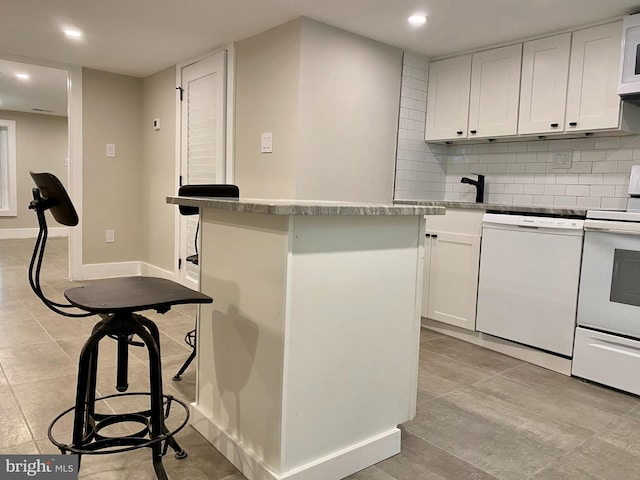 kitchen featuring white appliances, white cabinetry, a kitchen island, and backsplash