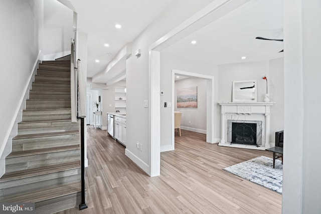 stairs with recessed lighting, wood finished floors, a high end fireplace, and baseboards