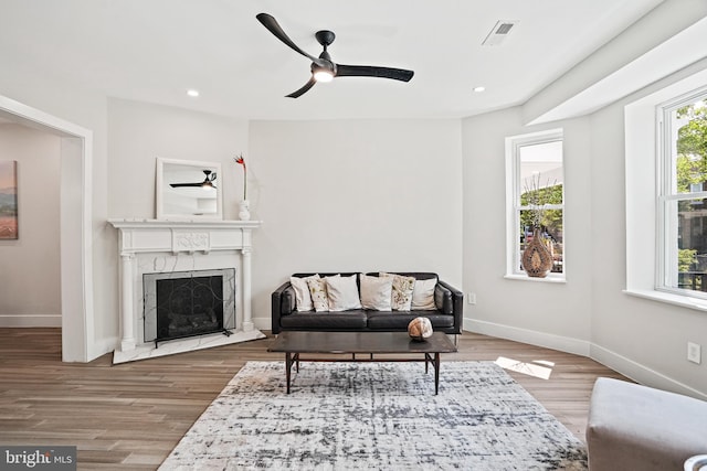 living area featuring baseboards, visible vents, wood finished floors, and a high end fireplace