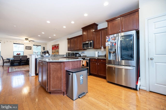 kitchen with light stone counters, a center island, stainless steel appliances, recessed lighting, and light wood-style floors