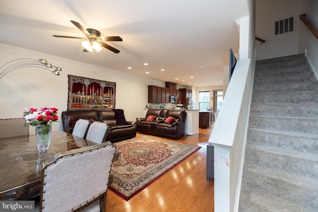 living area with crown molding, recessed lighting, visible vents, light wood-style floors, and stairs