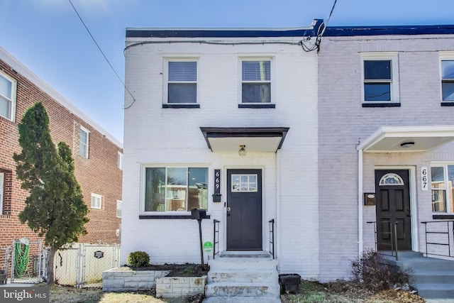 multi unit property with brick siding, fence, and a gate