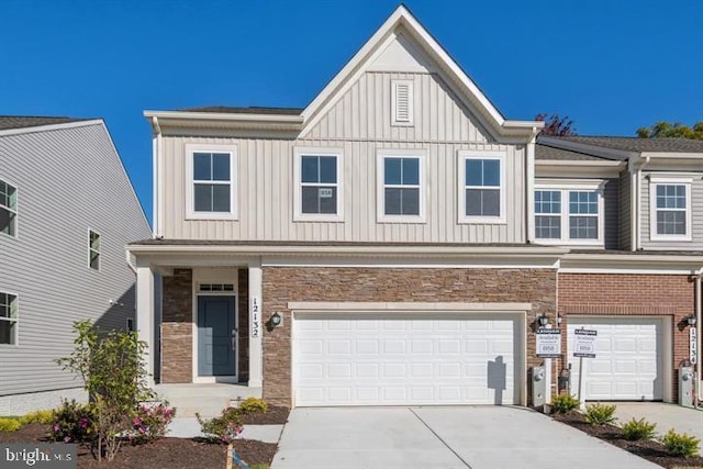 multi unit property featuring driveway, stone siding, board and batten siding, and an attached garage