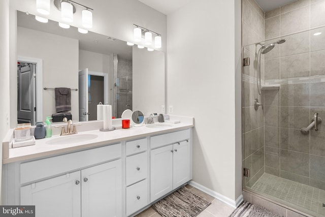 full bathroom with double vanity, a stall shower, and a sink