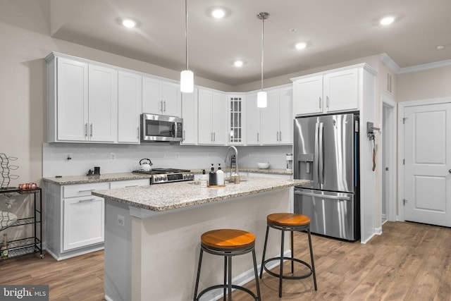 kitchen with stainless steel appliances, wood finished floors, and white cabinetry