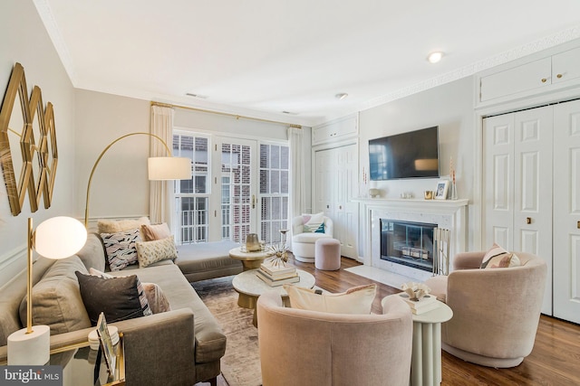 living area with dark wood-style floors, ornamental molding, a premium fireplace, and visible vents