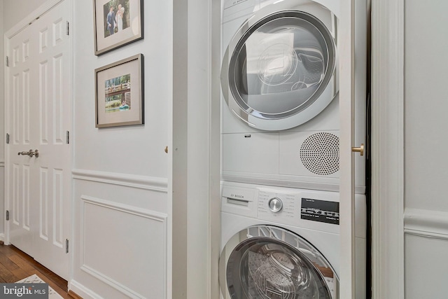 laundry area with dark wood-style floors, laundry area, and stacked washer and clothes dryer