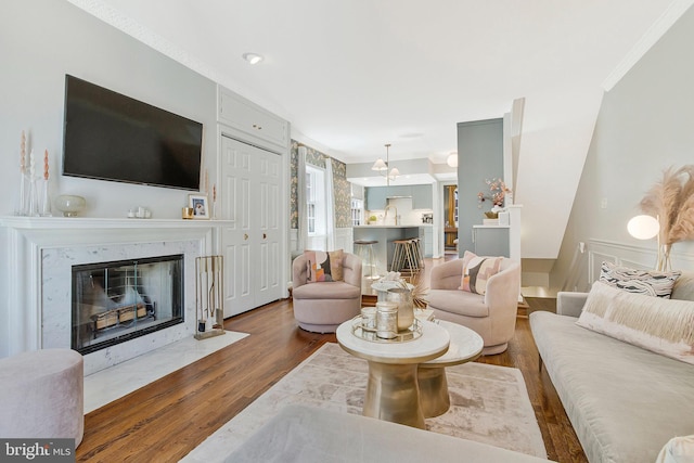 living area featuring ornamental molding, a premium fireplace, and wood finished floors