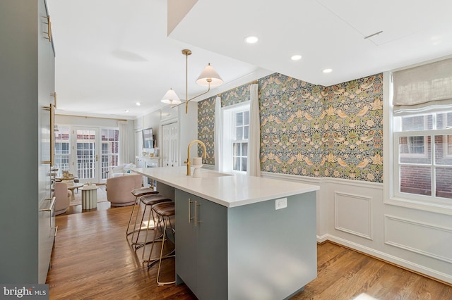 kitchen featuring a sink, a wainscoted wall, dark wood finished floors, and wallpapered walls