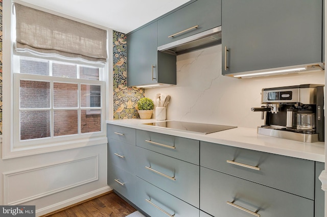 kitchen with under cabinet range hood, light countertops, dark wood finished floors, and gray cabinetry