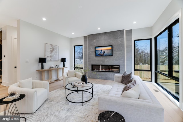 living area with a large fireplace, wood finished floors, and recessed lighting