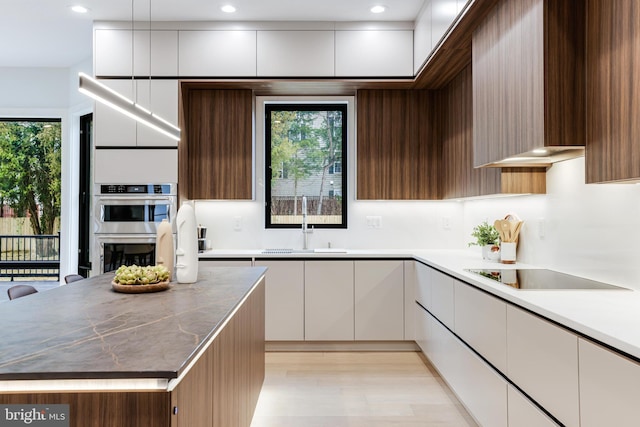 kitchen with plenty of natural light, stainless steel double oven, modern cabinets, and black electric cooktop