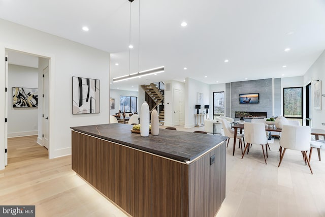 kitchen with dark countertops, recessed lighting, light wood-style flooring, a large fireplace, and modern cabinets