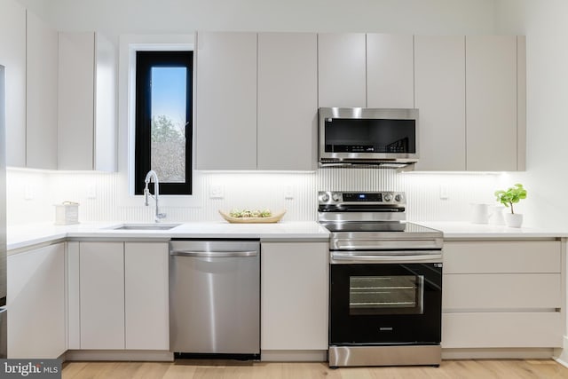 kitchen with modern cabinets, appliances with stainless steel finishes, light countertops, and a sink