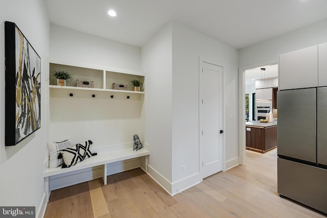 mudroom with recessed lighting, light wood-style flooring, and baseboards