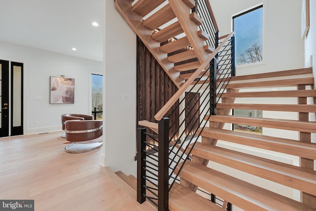 stairs with baseboards, wood finished floors, and recessed lighting