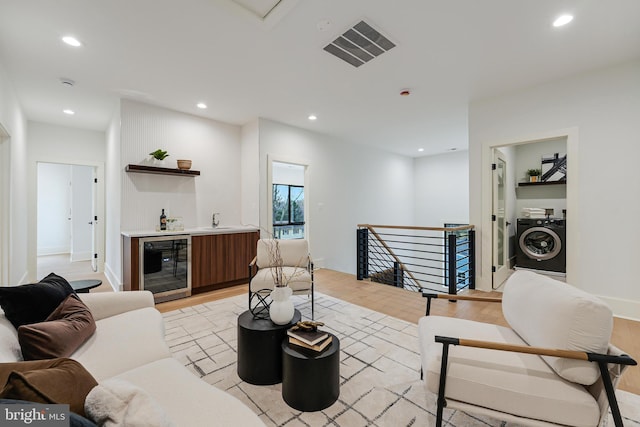 living area featuring wine cooler, light wood-type flooring, washer / dryer, and recessed lighting