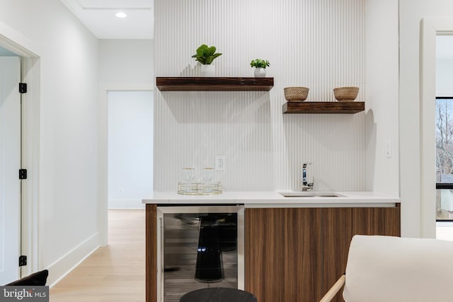 bar featuring wine cooler, indoor bar, recessed lighting, light wood-style floors, and a sink